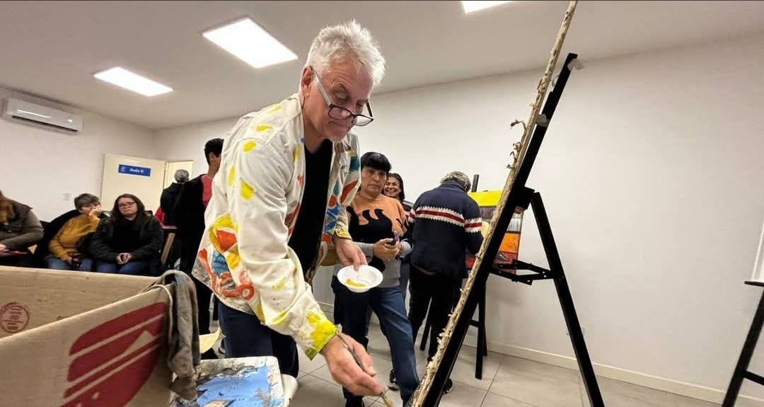 Alejandro Carlos Maass working with paint beside an easel.