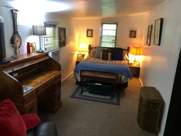 A warmly lit, rustic cabin room with a writing desk and bed.