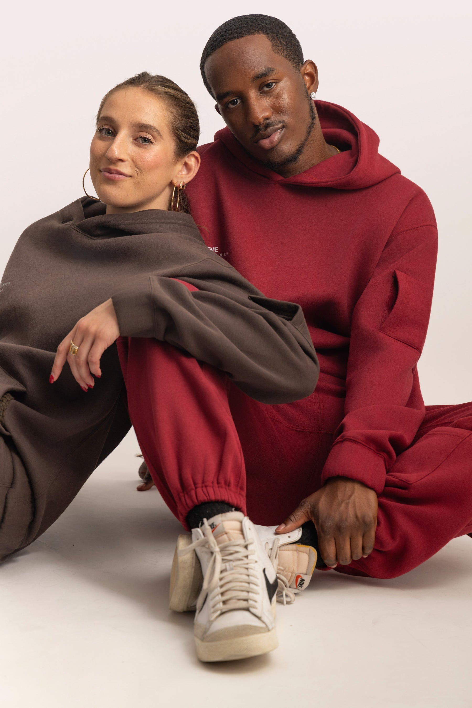 Two people seated together wearing brown and maroon SOLACE Collective COVE outfits.